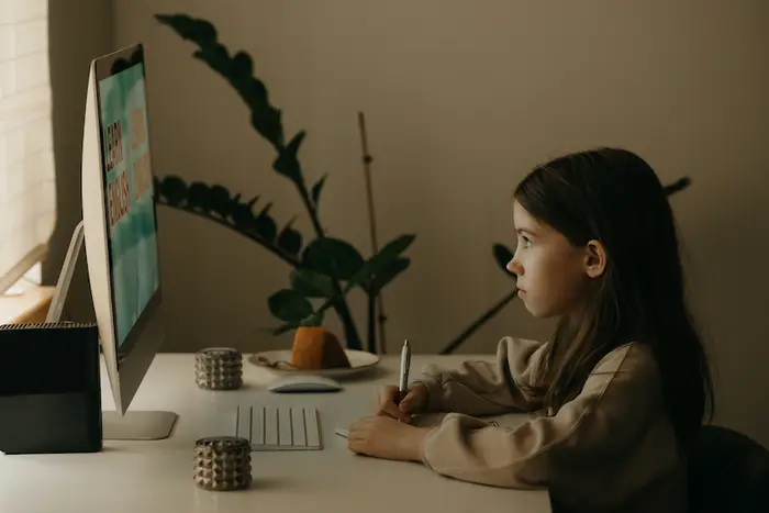 A young girl stares at the screen of her computer in a demonstration of remote learning.